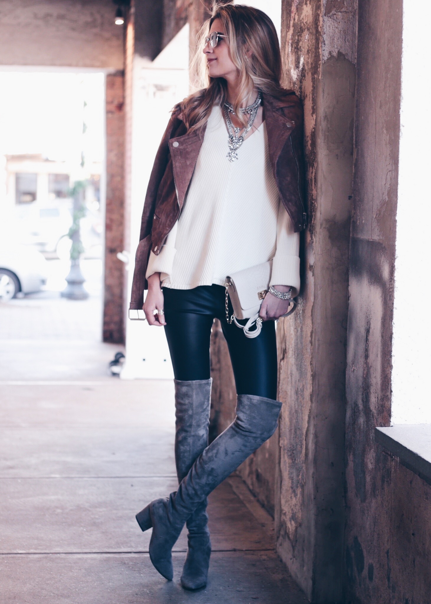 leather leggings outfit: over the knee suede boots and brown suede moto jacket with white free people sweater and bib necklace