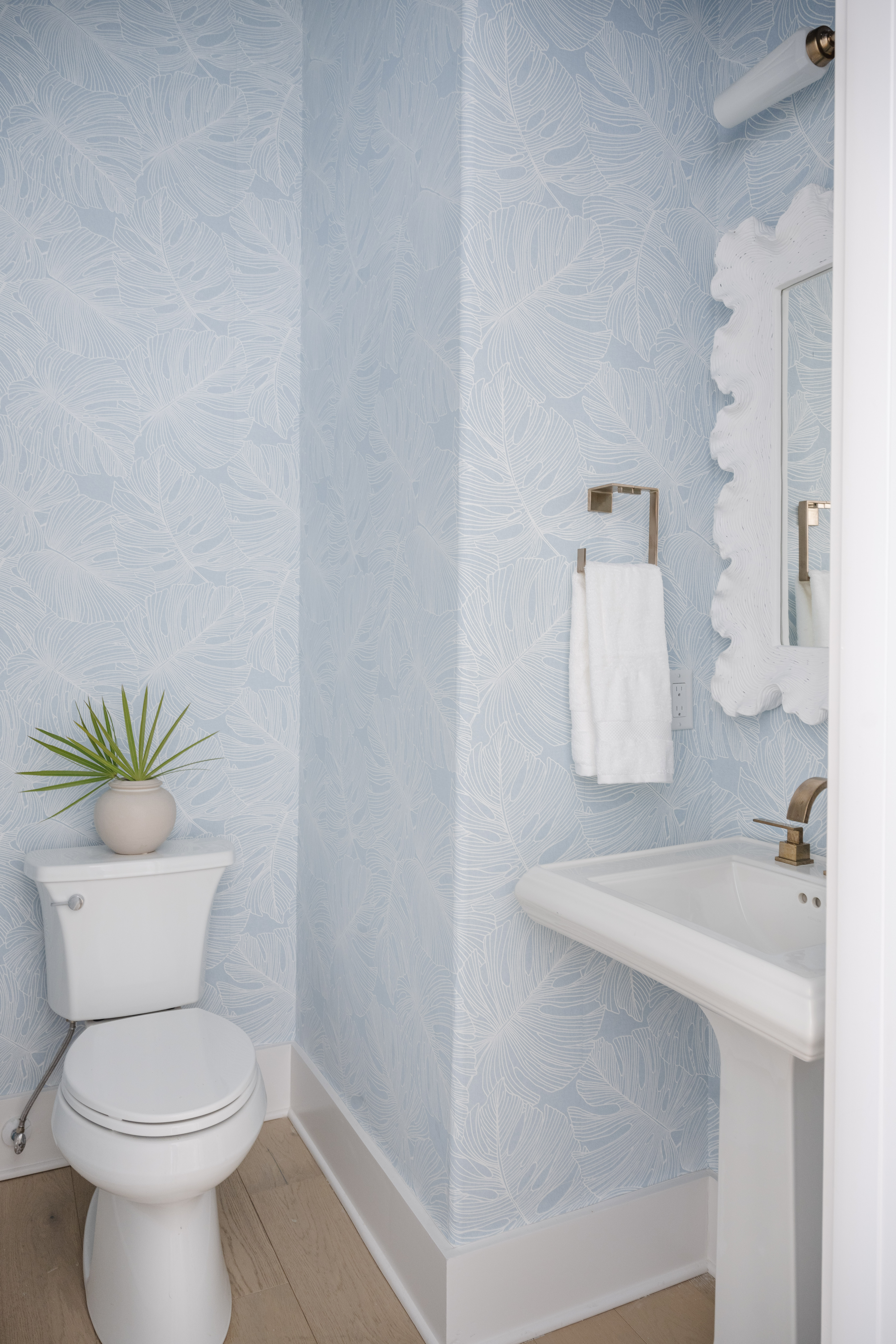 modern coastal powder room with monstero leaf wallpaper
