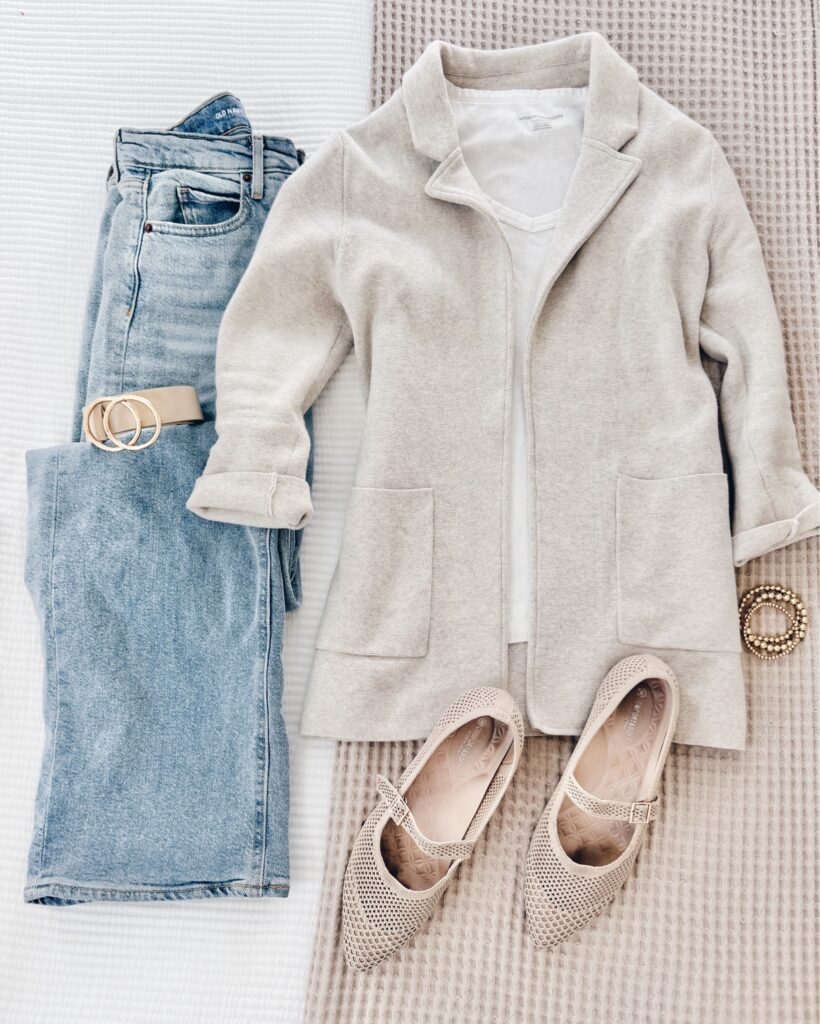 Effortlessly chic business casual outfit for women over 40 with light-wash denim, an oatmeal wool coat, white tee, nude Mary Jane flats, and a neutral belt.