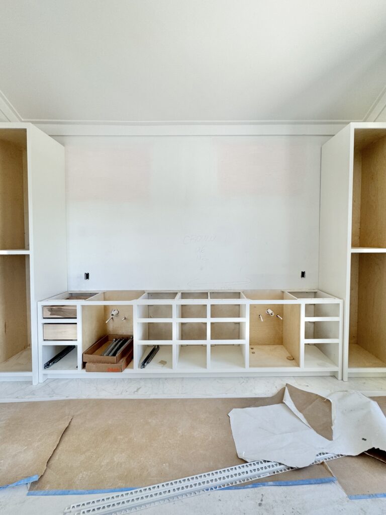 Built-in bathroom cabinetry with open shelves and plumbing installed, still awaiting drawer fronts and countertops in a newly built home.